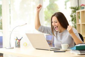 Euphoric winner watching a laptop on a desk winning at home